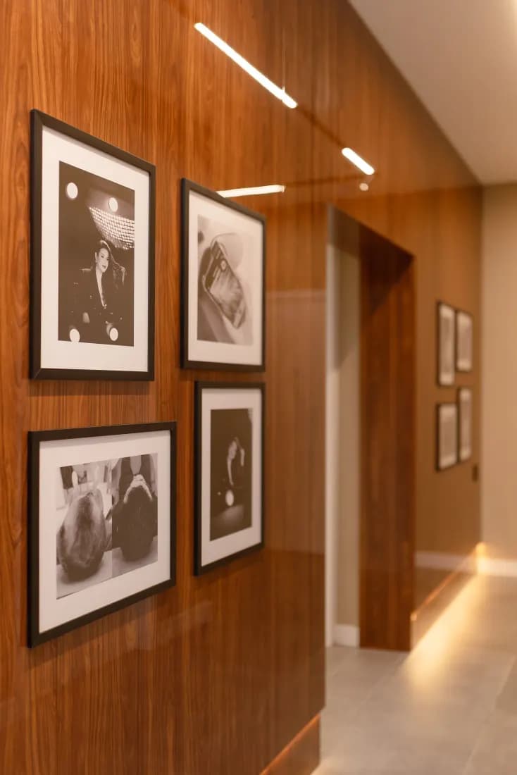 Corredor da clínica com painel de madeira e galeria em preto e branco